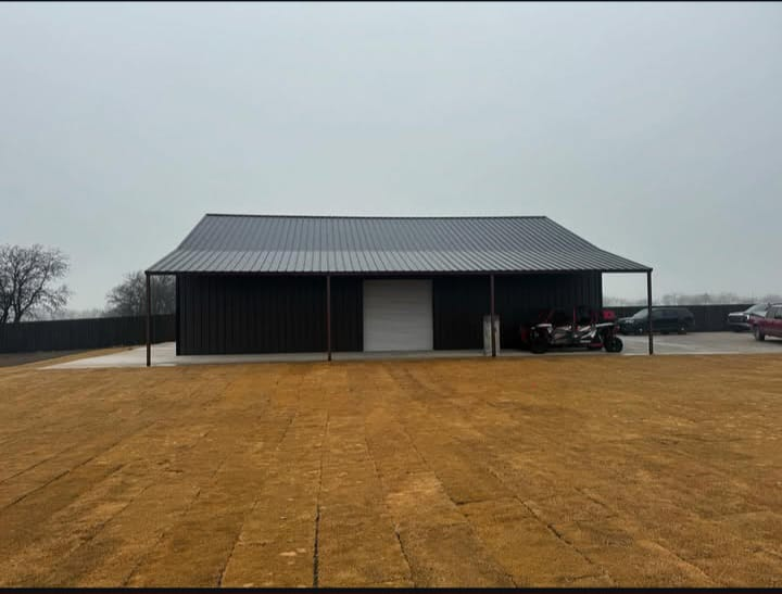 Metal structure with wide covered bays across a graded lot